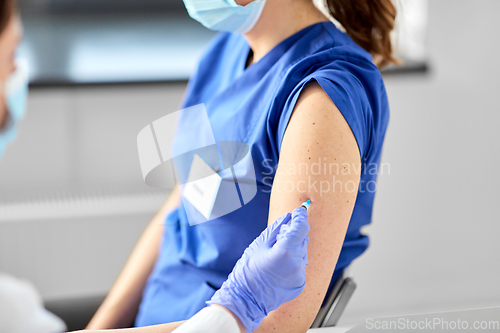 Image of doctor with syringe vaccinating medical worker