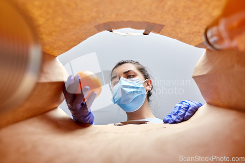 Image of woman in gloves and mask with food in paper bag