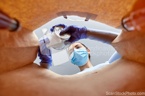 Image of woman in gloves and mask disinfecting food