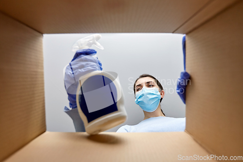 Image of woman in mask taking cleaning supplies from box