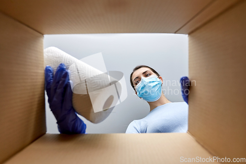 Image of woman in mask taking cleaning supplies from box