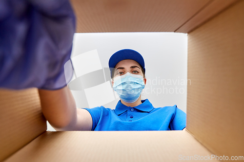 Image of woman in mask looking inside cardboard parcel box