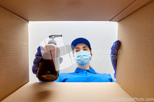 Image of woman in mask packing parcel box with cosmetics