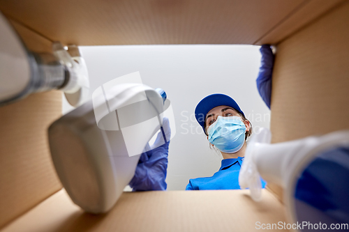 Image of woman in mask packing cleaning supplies in box