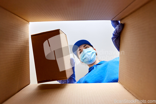 Image of woman in mask packing box to parcel