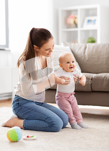 Image of happy mother playing with little baby at home