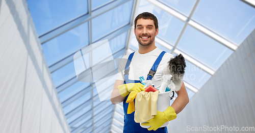 Image of male cleaner with cleaning supplies in glasshouse