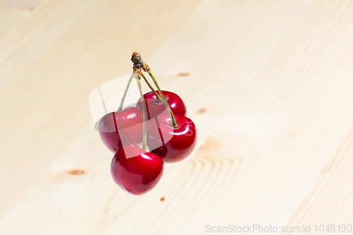 Image of Four organic sweet cherries isolated on a wooden background