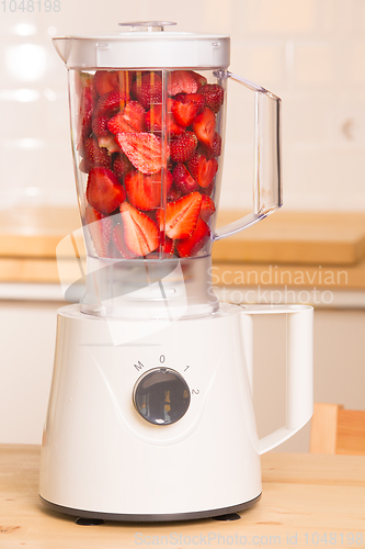 Image of fresh strawberries in white Blender on a wooden table