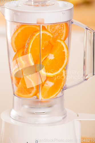 Image of White blender with juicy oranges on a wooden table