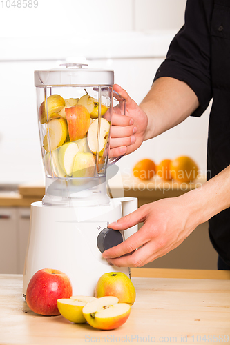 Image of White blender with apples on a wooden table. 