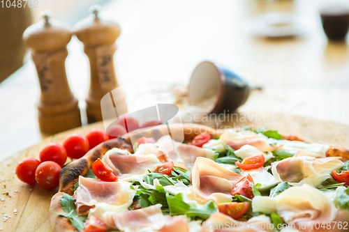 Image of Pizza with cherry tomatoes, prosciutto and ruccola