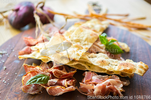 Image of Homemade prosciutto and basil on a wooden board