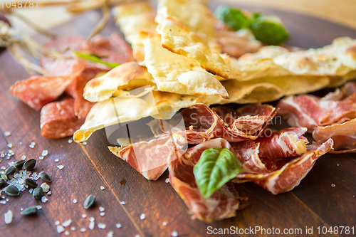 Image of Homemade prosciutto and basil on a wooden board