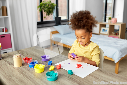 Image of little girl with modeling clay playing at home