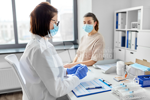 Image of female doctor with syringe and patient at hospital