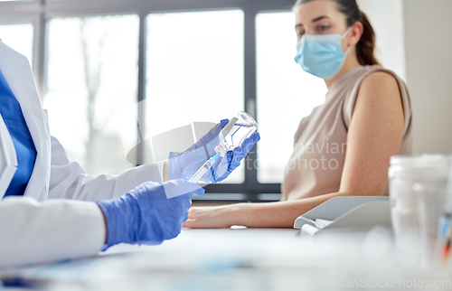 Image of female doctor with syringe vaccinating patient