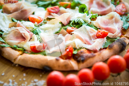 Image of Pizza with cherry tomatoes, prosciutto and ruccola