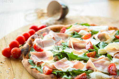 Image of Pizza with cherry tomatoes, prosciutto and ruccola