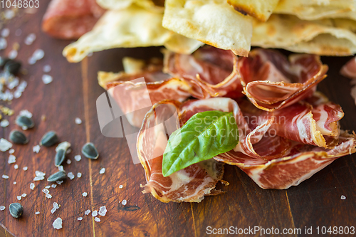 Image of Homemade prosciutto and basil on a wooden board