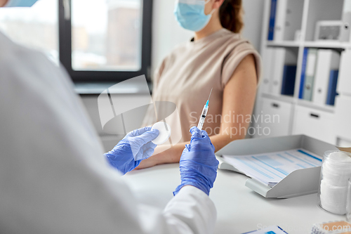 Image of female doctor with syringe vaccinating patient