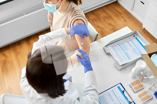 Image of female doctor with syringe vaccinating patient