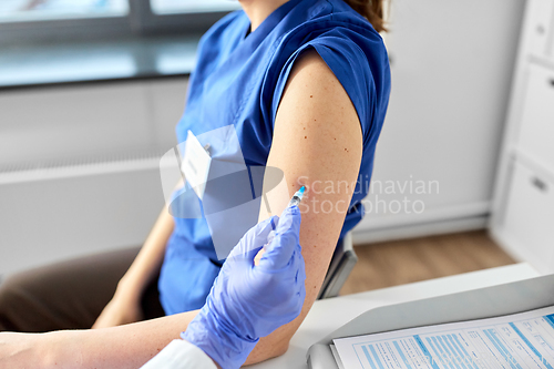 Image of doctor with syringe vaccinating medical worker