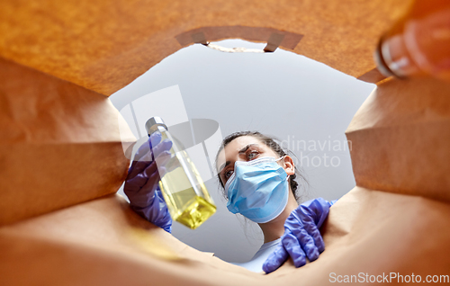 Image of woman in gloves and mask with food in paper bag