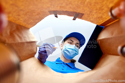 Image of delivery girl in gloves and mask with food in bag