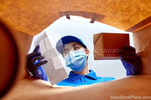 Image of delivery girl in gloves and mask with food in bag