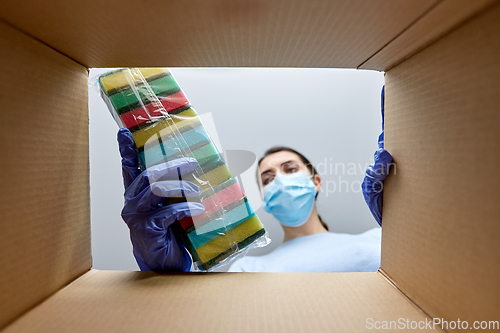 Image of woman in mask taking cleaning supplies from box