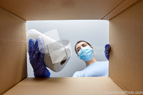 Image of woman in mask taking cleaning supplies from box