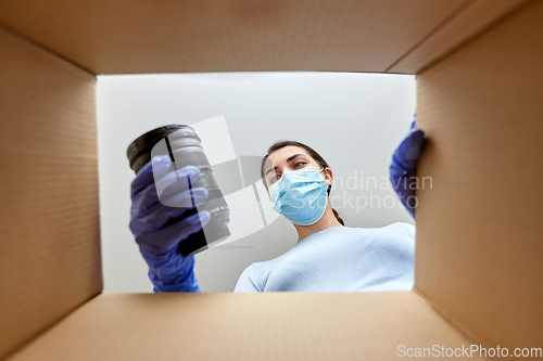 Image of woman in mask packing camera into parcel box