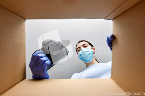 Image of woman in mask packing camera into parcel box