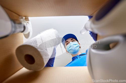 Image of woman in mask packing cleaning supplies in box