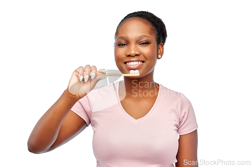 Image of smiling woman with toothpaste on wooden toothbrush