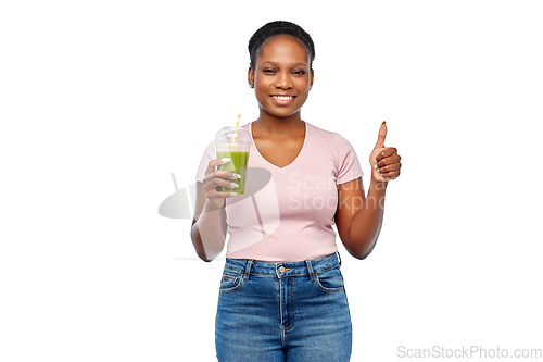 Image of happy african american woman drinking green juice