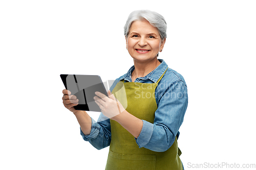 Image of happy senior woman in garden apron with tablet pc