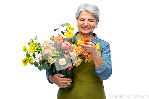 Image of smiling senior woman in garden apron with flowers