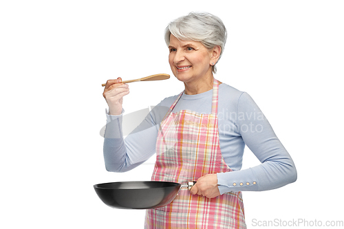 Image of smiling senior woman in apron with frying pan