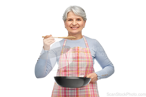 Image of smiling senior woman in apron with frying pan