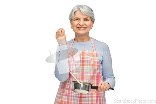 Image of senior woman in apron with pot cooking food