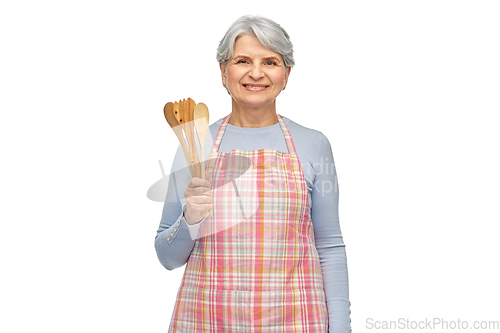 Image of smiling senior woman in apron with wooden spoons