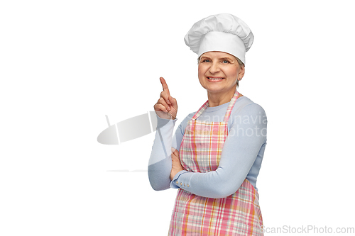 Image of smiling senior woman or chef pointing finger up