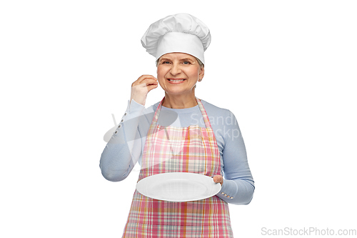 Image of smiling senior woman or chef holding empty plate