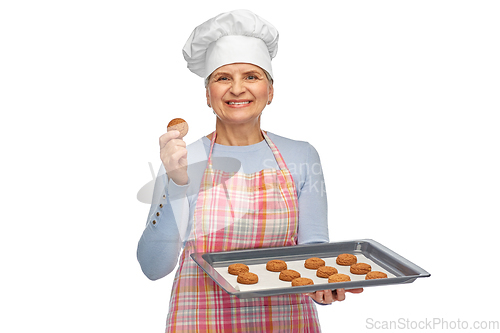 Image of senior woman in toque with cookies on baking pan