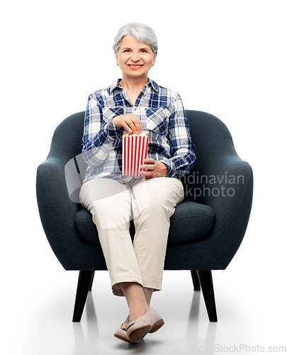 Image of senior woman eating popcorn sitting in armchair