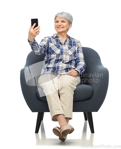 Image of smiling senior woman sitting in modern armchair