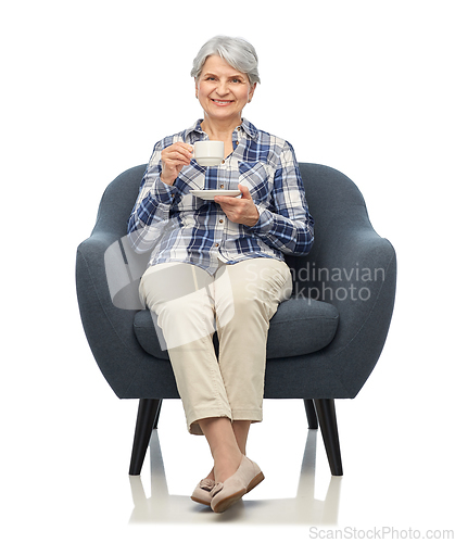 Image of smiling senior woman drinking coffee in armchair