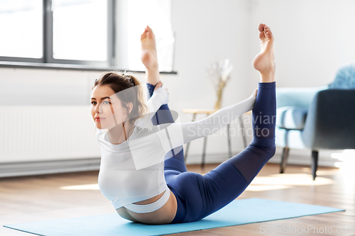 Image of young woman doing bow pose at yoga studio